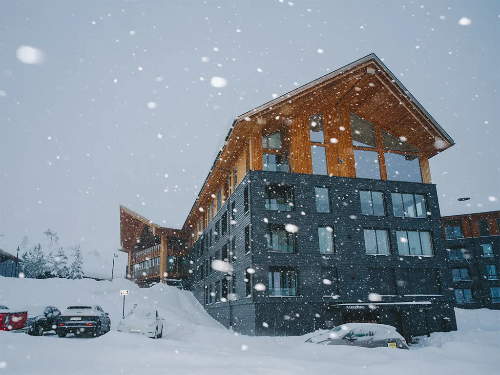 Fýri Resort i Hemsedal under kraftig snøfall om vinteren med moderne tre- og steinfasade