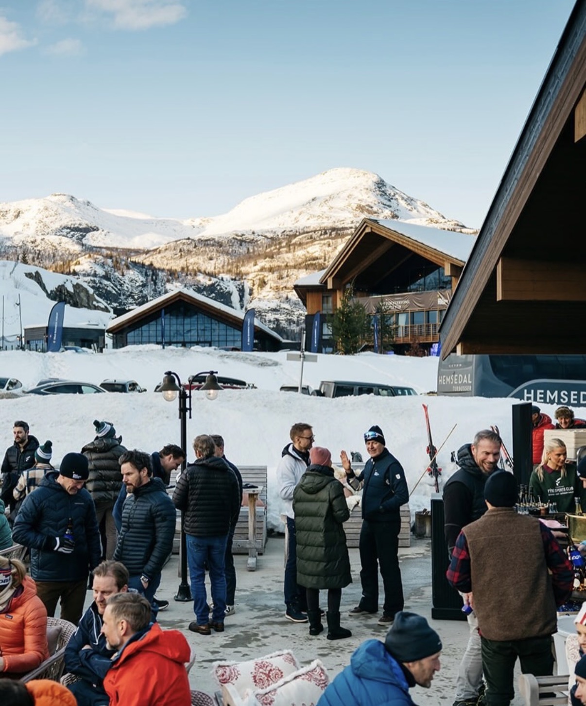 Folk samles på en utendørs servering i snødekt fjellandskap