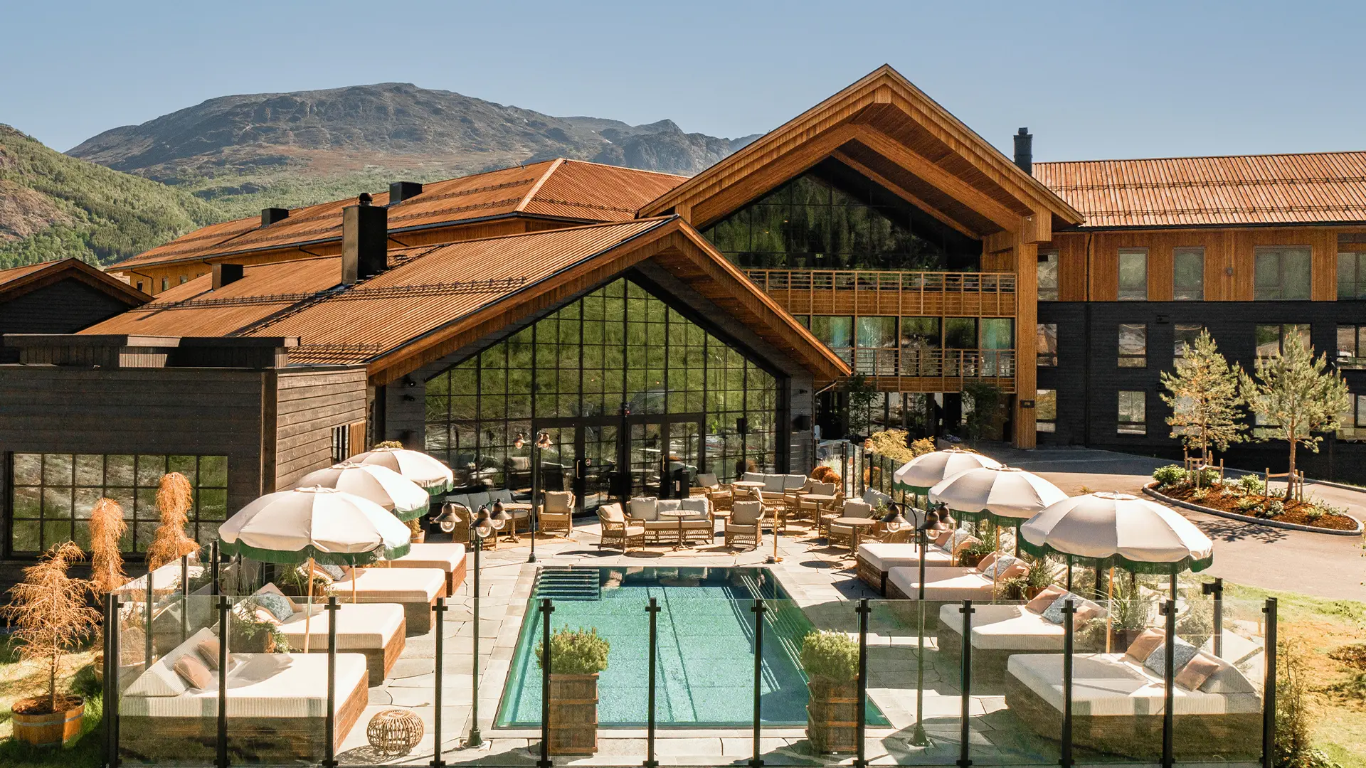 Utendørs poolområde på Fýri Resort i Hemsedal om sommeren med solsenger og fjellutsikt