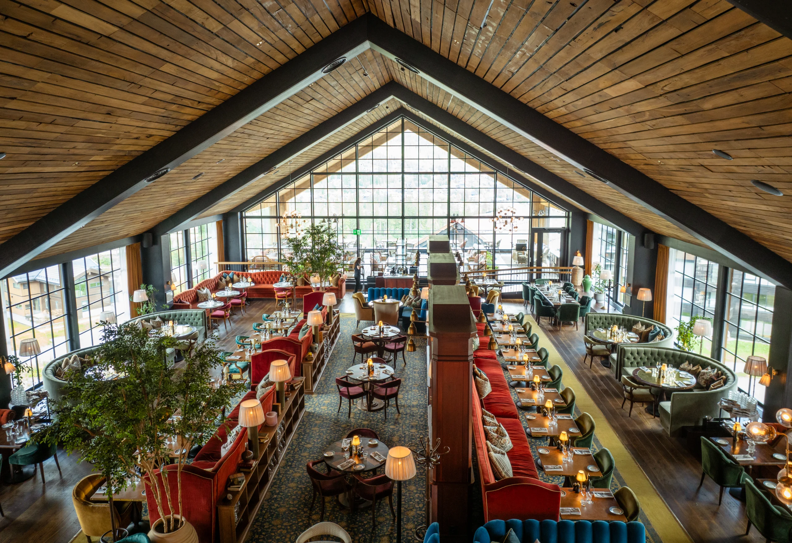 Spacious restaurant dining room with a vaulted wood ceiling, large windows, and colorful booth seating