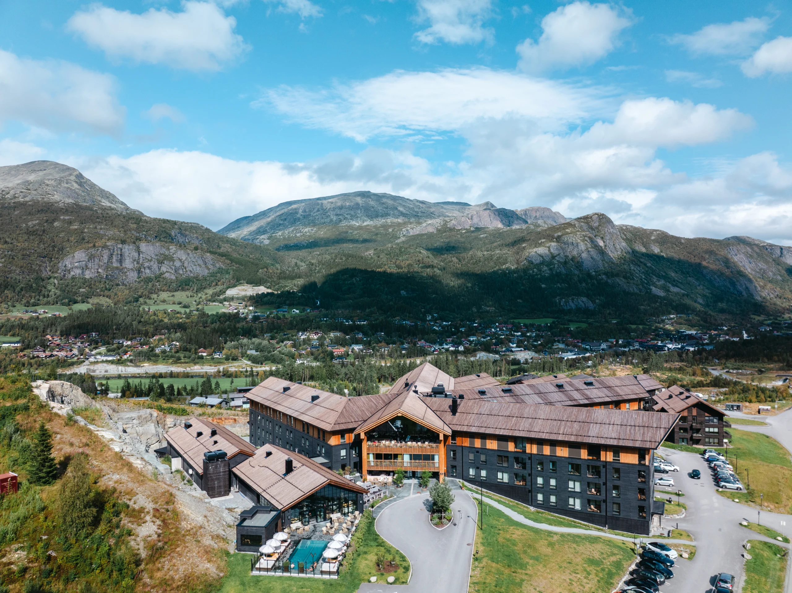 Aerial view of a mountain resort surrounded by a village, forested hills, and rugged mountains