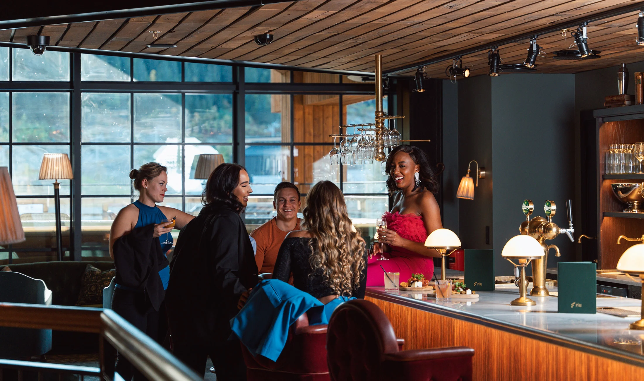 Five friends chat and enjoy drinks at a stylish bar
