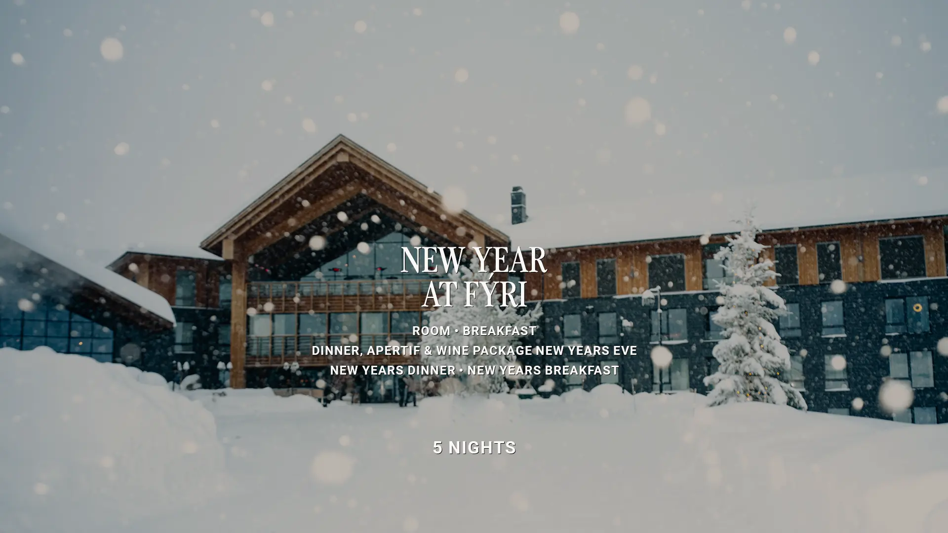 Snow falling in front of Fýri Hotel, with a snow-covered spruce tree and a timber and dark-clad building. Text overlay: “New Year at Fýri – Room, Breakfast, Dinner, Aperitif & wine package New Year’s Eve, New Year’s Dinner, New Year’s Breakfast, 5 nights”.